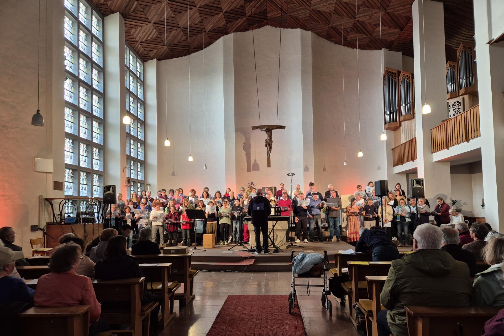 Mehr als 80 Sängerinnen und Sänger singen in einer modern gestalteten Kirche.