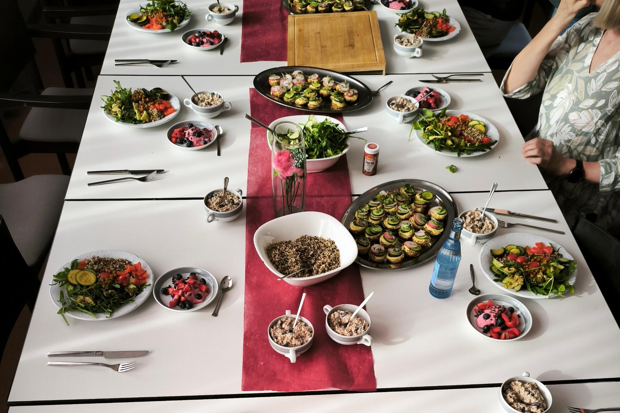 Gemeinsames Essen an einem liebevoll gedeckten Tisch mit vielfältigen, antientzündlichen Gerichten wie frischen Salaten, Gemüse, Beeren-Desserts und gesunden Snacks.