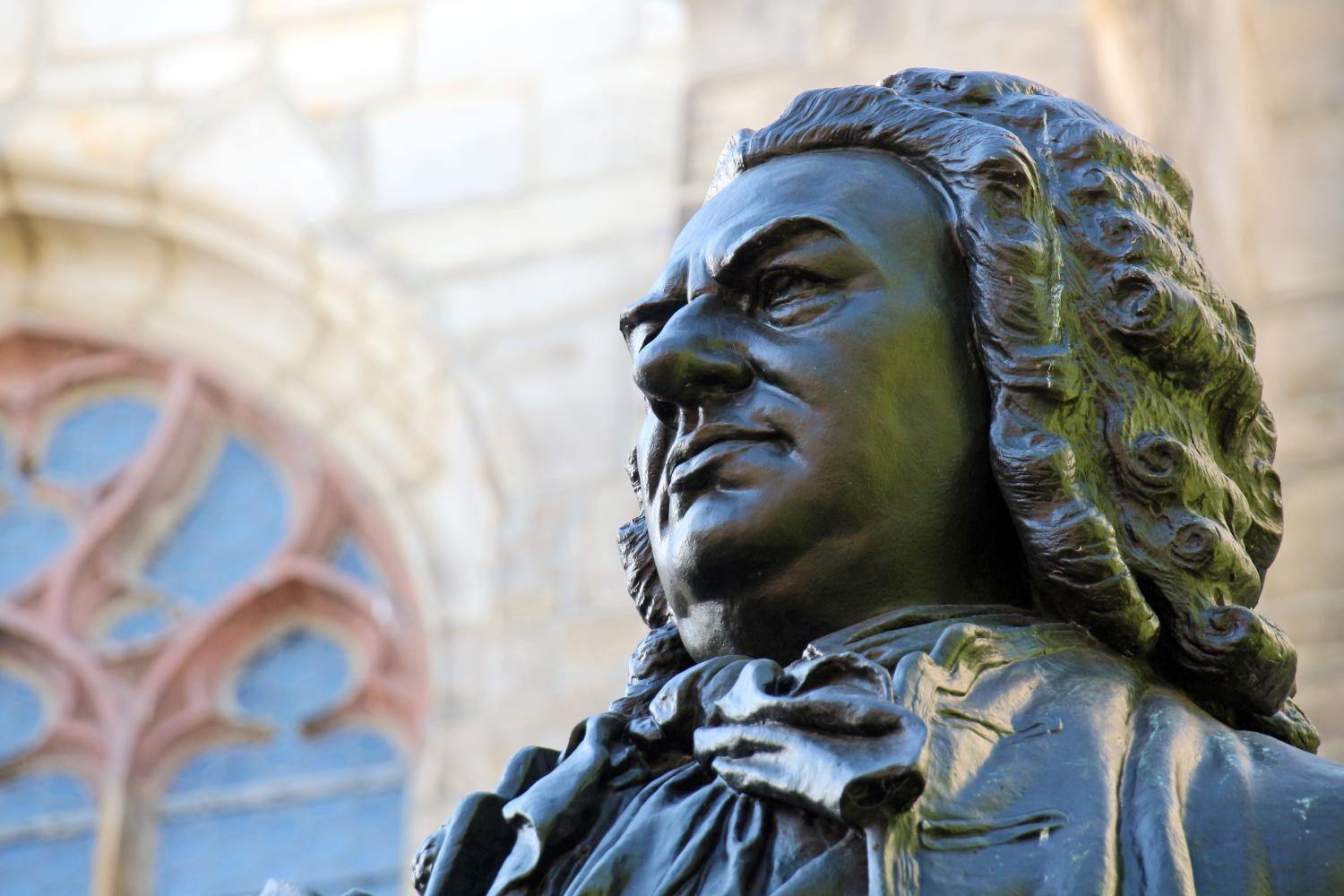 Bronzestatue eines Mannes mit Lockenperücke vor einer Kirche