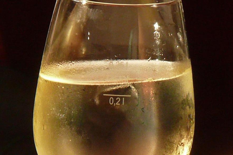 Gefülltes Weißweinglas mit Kondenswassertropfen am Glasrand