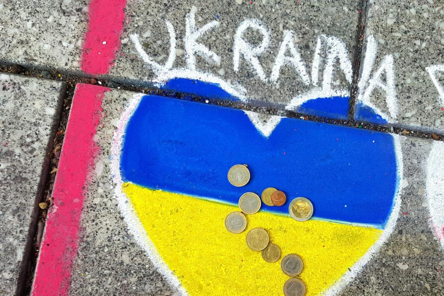 Herz in ukrainischen Farben mit Münzen auf Gehweg gemalt.