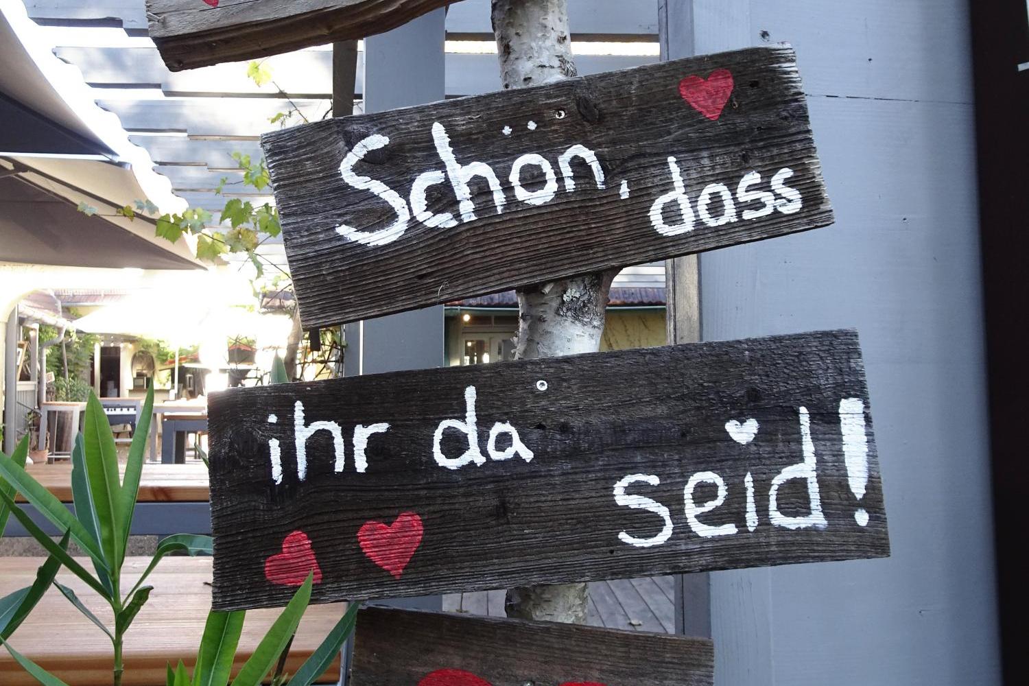 Rustikale Holzschilder mit einem Willkommensgruß und Herzen.