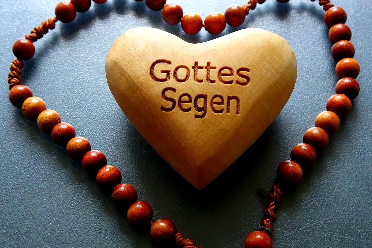 Holzherz mit der Gravur 'Gottes Segen' in einer Perlenkette geformt als Herz.