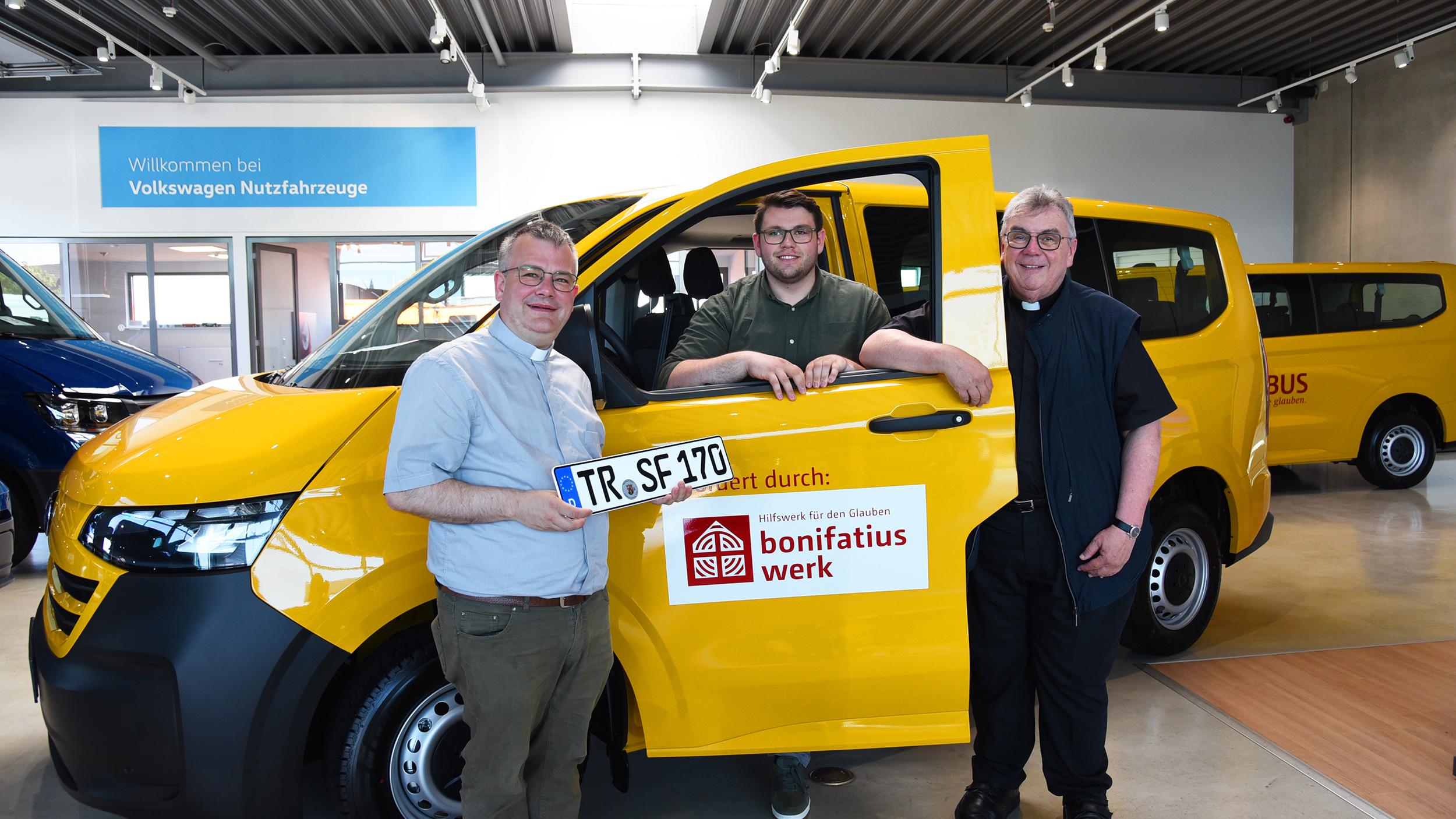 Dekan Christian Heinz und Noah Bach, Seminarist in Trier und Ehrenamtlicher in der Pfarrei, freuen sich über den neuen BONI-Bus, der ihnen von Bonifatiuswerk-Generalsekretär Monsignore Georg Austen überreicht wurde (v.l.).